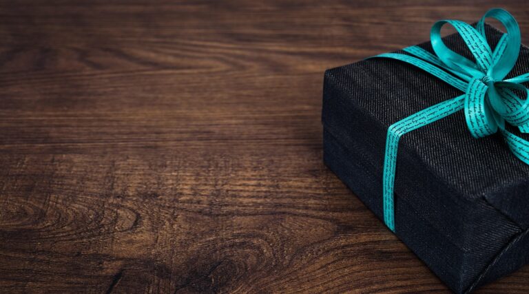 a black box with a blue ribbon on a wooden surface